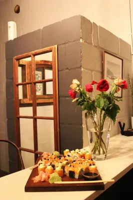 a plate of sushi on a table with a vase of roses at Lategansrus at Helpmekaar Farm in Wellington