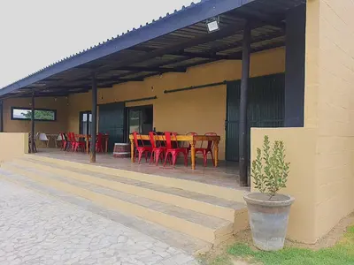 a patio with red tables and chairs on a building at Lategansrus at Helpmekaar Farm in Wellington