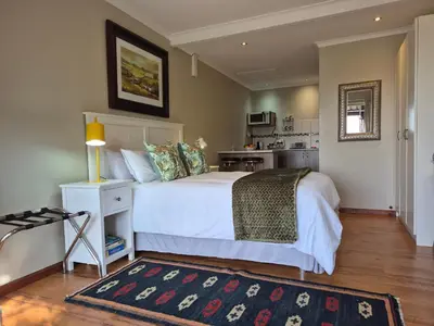 a bedroom with a white bed and a kitchen at Mistys Studio Durbanville in Durbanville