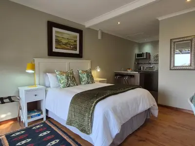 a bedroom with a large white bed and a kitchen at Mistys Studio Durbanville in Durbanville