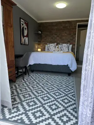 a bedroom with a bed and a desk in a room at Three on Firmount in Somerset West