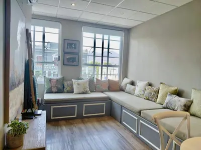 a living room with a large couch in front of two windows at The Botanic High Gold in Paarl