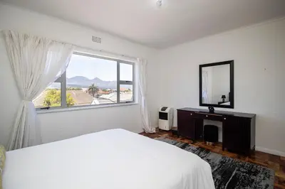 a bedroom with a bed and a mirror and a window at Mountain View Coastal Retreat in Strand