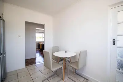 a dining room with a white table and chairs at Mountain View Coastal Retreat in Strand