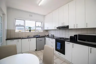 a kitchen with white cabinets and a stove top oven at Mountain View Coastal Retreat in Strand