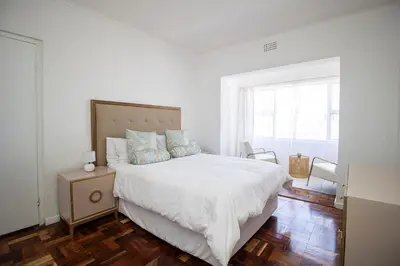 a white bedroom with a bed and a window at Mountain View Coastal Retreat in Strand