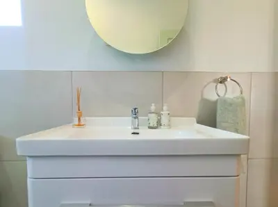 a bathroom with a white sink and a mirror at Helderberg Hideaway Loft in Somerset West