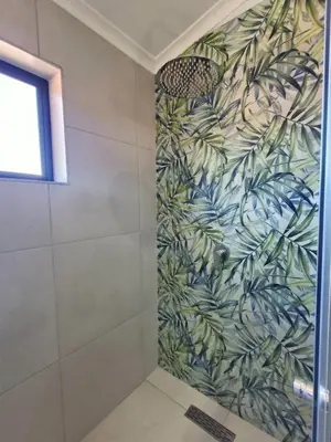 a bathroom with a shower with a tropical wallpaper at Helderberg Hideaway Loft in Somerset West