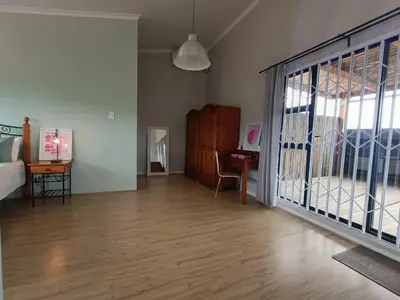 a living room with a bed and a sliding glass door at Helderberg Hideaway Loft in Somerset West