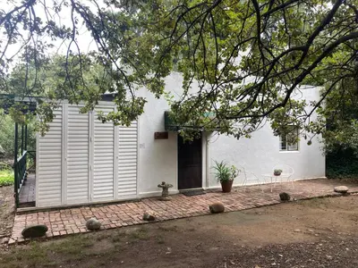 a white house with a door and a brick patio at William's Cottage in Franschhoek