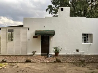 a white house with two cats sitting in front of it at William's Cottage in Franschhoek