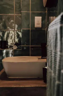 a bath tub in a bathroom with a green tiled wall at The Crescent Hideaway in Franschhoek