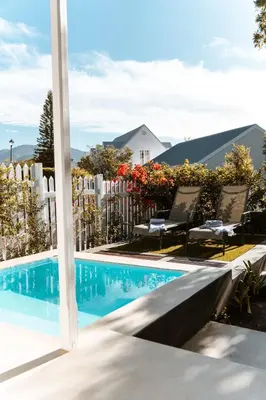 a swimming pool with two chairs and a fence at The Crescent Hideaway in Franschhoek