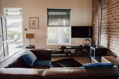a living room with a brown couch and a brick wall at The Crescent Hideaway in Franschhoek