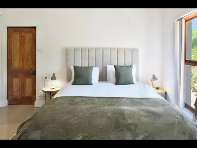 a bedroom with a large white bed with green pillows at The Manor House at Roubaix Estate in Franschhoek