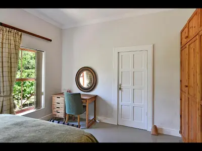 a bedroom with a bed and a desk and a window at The Manor House at Roubaix Estate in Franschhoek