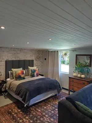 a bedroom with a large bed and a brick wall at 7th Heaven Guest Cottage in Paarl