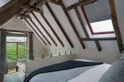 a bedroom with white walls and wooden beams at Skaap huis in Sir Lowryʼs Pass