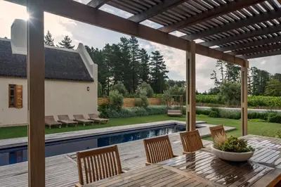 a patio with a table and chairs and a swimming pool at Skaap huis in Sir Lowryʼs Pass