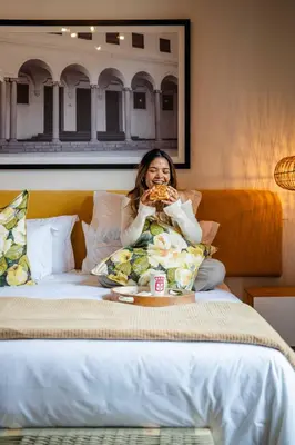 a woman sitting on a bed eating a pizza at Paarl Boutique Hotel in Paarl