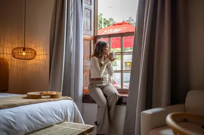 a woman sitting in a window drinking a drink at Paarl Boutique Hotel in Paarl