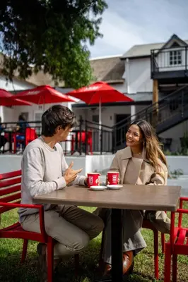 two women sitting at a table with coffee cups at Paarl Boutique Hotel in Paarl