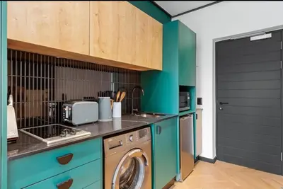 a kitchen with green cabinets and a washer and dryer at Luxe at Nine Palms Near Canal Walk in Cape Town