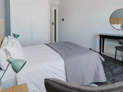 a bedroom with a bed with a chair and a desk at Romilly Beachfront 92 in Strand