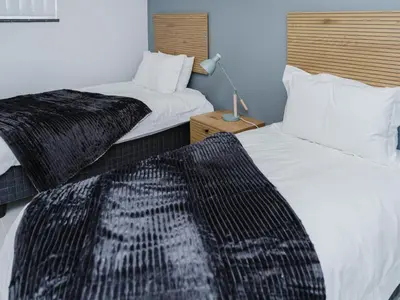 two beds in a hotel room with white sheets and black blankets at Romilly Beachfront 92 in Strand