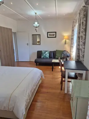 a bedroom with a bed and a couch and a table at Pine House - self-catering in Cape Town