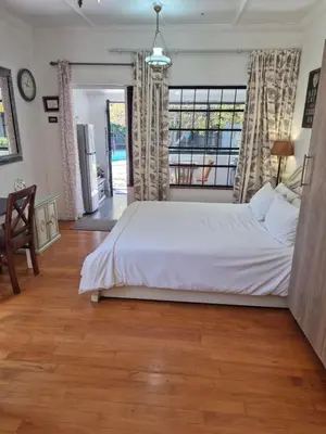 a bedroom with a white bed and a large window at Pine House - self-catering in Cape Town