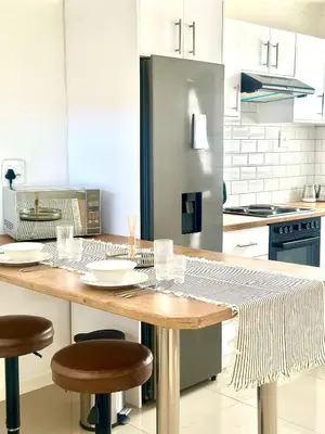 a kitchen with a wooden table with stools in it at Lalla Cottages - Cape Town in Cape Town
