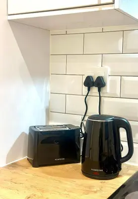 a black toaster sitting on a counter next to a microwave at Lalla Cottages - Cape Town in Cape Town
