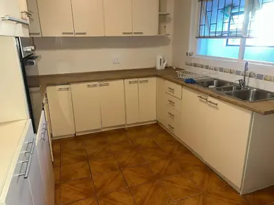 a kitchen with white cabinets and a wooden floor at triplediz in Blackheath