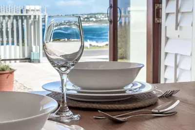 a table with a glass of wine on a table with a view at Geheim Luxury Seafront in Hermanus