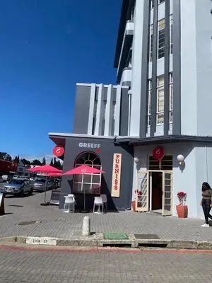 a woman walking past a building with a cafe at Salt & Cellar - Paarl - Self Catering Apartment in Paarl