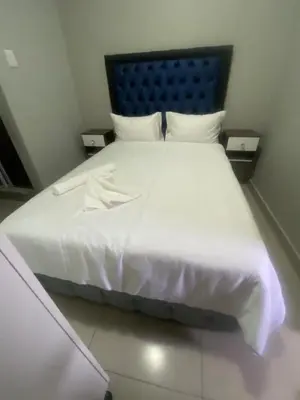 a white bed with a blue headboard and white sheets at JM B&B - Mandalay in Mandalay