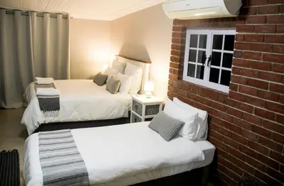 a hotel room with two beds and a brick wall at Firehouse selfcatering Garden Cottage no 2 in Wellington