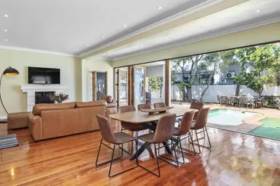 a living room with a table and chairs at Spacious Claremont Home with Pool Fireplace in Cape Town