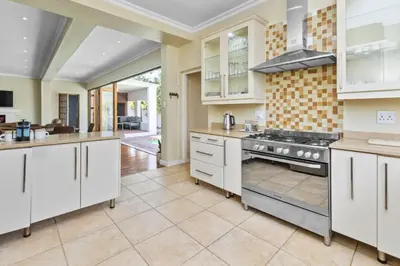 a kitchen with white cabinets and a stove at Spacious Claremont Home with Pool Fireplace in Cape Town