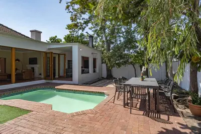 a patio with a table and chairs and a swimming pool at Spacious Claremont Home with Pool Fireplace in Cape Town