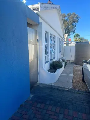 a white house with a blue wall and a garage at home away in Bellville South