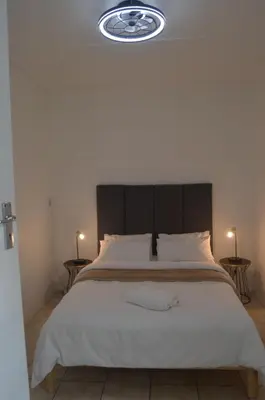 a bedroom with a large bed with a black headboard at Oasis - Renovated - Queen extra length bed apartment in Cape Town