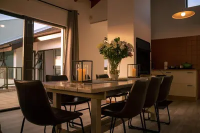 a dining room table with chairs and a vase of flowers at Voëlklip Family House in Hermanus