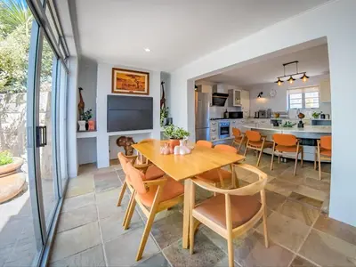 a kitchen and dining room with a wooden table and chairs at Cape Joy - BRAND NEW luxury villa just rolled out in Cape Town, Plattekloof in Plattekloof