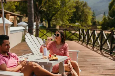 a man and a woman sitting at a table drinking wine at Le Pommier Wine Estate in Stellenbosch