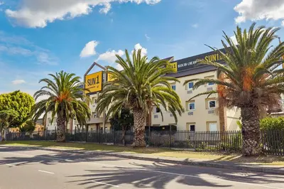 a hotel with palm trees in front of a fence at SUN1 Parow Cape Town in Avondale