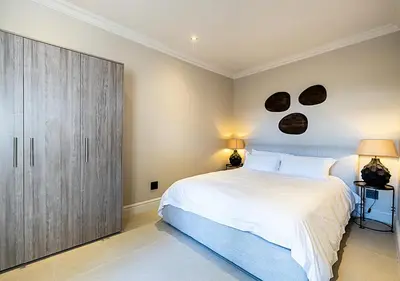 a bedroom with a large white bed and a cabinet at Von Wyn Berg in Stellenbosch