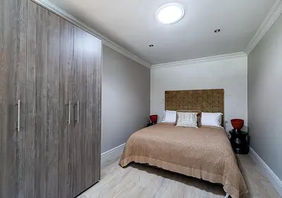 a bedroom with a bed and a large wooden cabinet at Von Wyn Berg in Stellenbosch