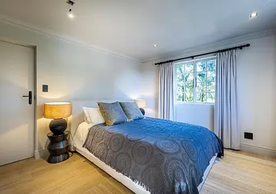 a bedroom with a bed with a blue comforter and a window at Von Wyn Berg in Stellenbosch